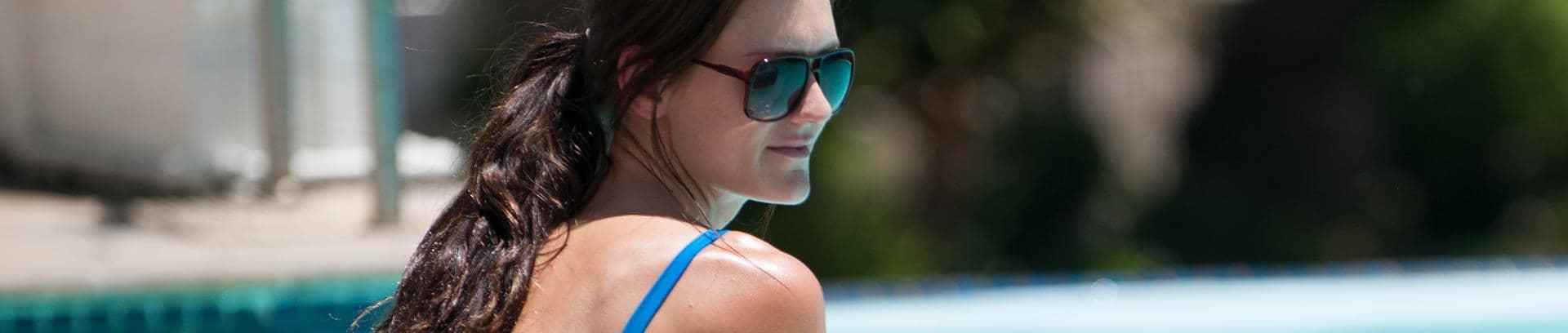Woman sat by the pool, with sunglasses on, enjoying her holiday